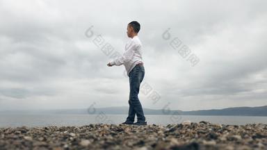 男孩<strong>扔石头</strong>跳过海水表面夏天假期概念慢运动